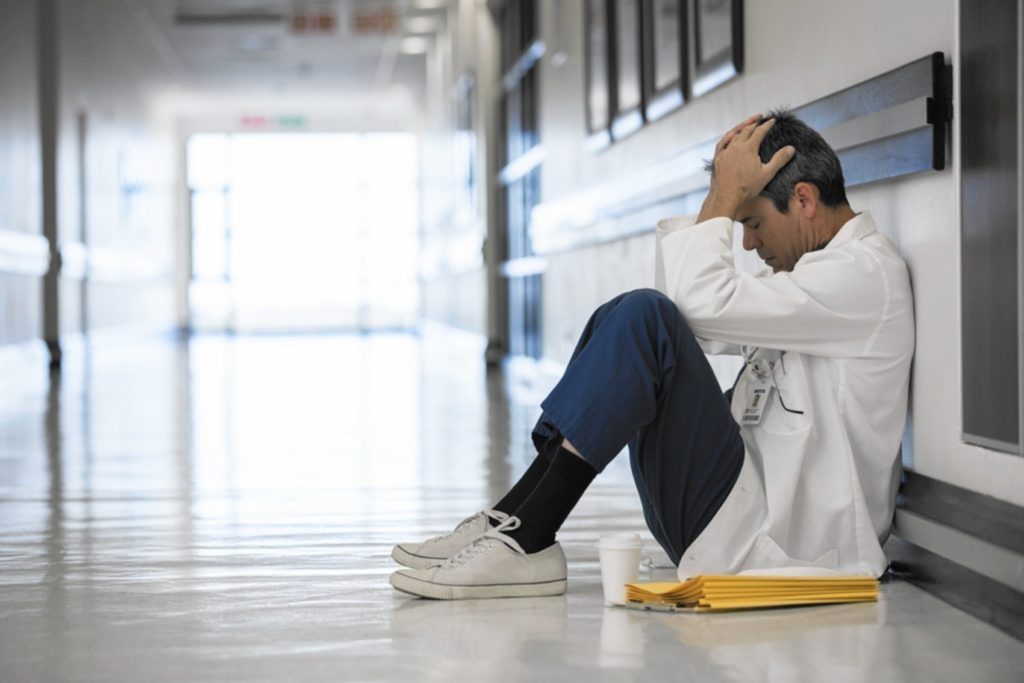 physician sitting outside medical room suffering from burnout