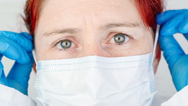 hospital staff engagement - burned out medical nurse putting mask on